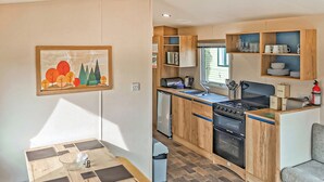 A compact kitchen with wooden cabinets, a stove, and a sink. - Gold Plus 3 Sleeps 6 (Pet) (New Quay)