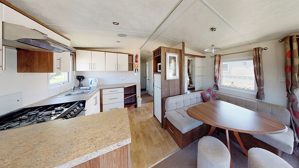 A compact RV kitchen with a dining area, including a table and seating, and a small kitchenette. - Gold Plus 3 Sleeps 6 (Pet) (New Quay)