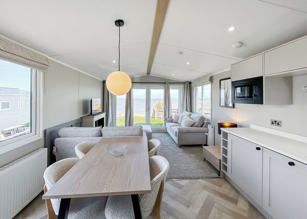A modern kitchen with a dining area, a television, and a view of the outdoors.