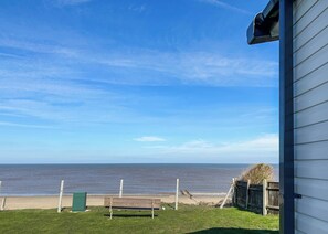 A view of the ocean from a house with a bench in the foreground. - 4 bedroom accommodation in Bacton-on-Sea (Bacton-on-Sea)