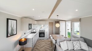 A modern kitchen with a dining area, a sofa, and a pendant light.