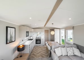 A modern kitchen with a dining area, a sofa, and a pendant light. - 4 bedroom accommodation in Bacton-on-Sea (Bacton-on-Sea)