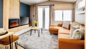 Un salon moderne avec une cheminée, un canapé, un téléviseur et un coin repas.