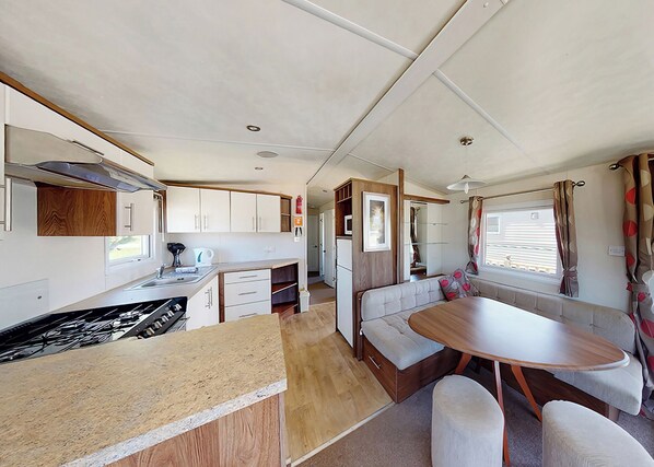 Een compacte RV-keuken met een eethoek, inclusief een tafel en zitplaatsen, en een kleine kitchenette.