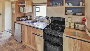 Une cuisine compacte équipée d’une cuisinière intégrée, d’un évier et d’un petit réfrigérateur.