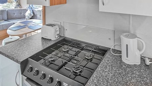 A compact kitchen with a gas stove, a coffee maker, and a toaster. - Gold Plus 3 Sleeps 6 (New Quay)