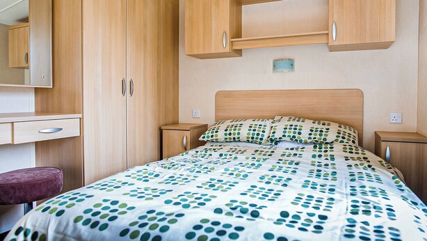 Une chambre à coucher comprenant un lit, un bureau, une chaise et des armoires en bois.