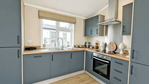 A modern kitchen with grey cabinets, a wooden countertop, a built-in oven, and a window with a valance. - 2 bedroom accommodation in Market Bosworth, near Nuneaton (Market Bosworth, near Nuneaton)