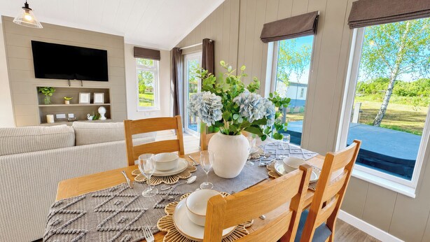 A dining area with a table set for four, a sofa, a television, and a view of the outdoors. - 2 bedroom accommodation in Market Bosworth, near Nuneaton (Market Bosworth, near Nuneaton)