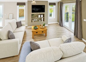 A living room with a sofa set, a coffee table, a TV, and a large window with curtains.