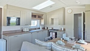 A compact kitchen with a built-in oven, microwave, and stove. There is a dining area with a table and chairs, and a window above the sink.