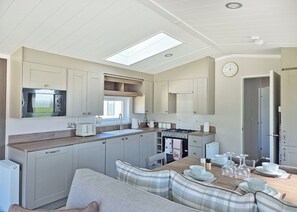 A compact kitchen with a built-in oven, microwave, and stove. There is a dining area with a table and chairs, and a window above the sink.