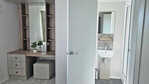 A bedroom with a built-in wardrobe, a bedside table, and a potted plant.