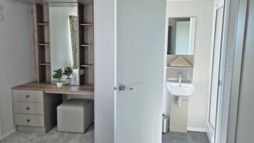 Une chambre avec un placard intégré, une table de chevet et une plante en pot.