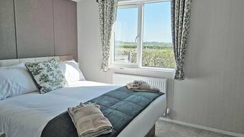 Une chambre à coucher avec un lit, une fenêtre avec des rideaux, un radiateur et une vue sur la verdure à l’extérieur.