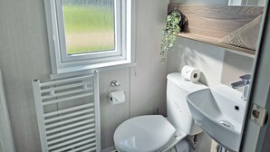 A compact bathroom with a toilet, sink, and window.