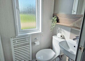 Un baño pequeño con inodoro, lavamanos y ventana.