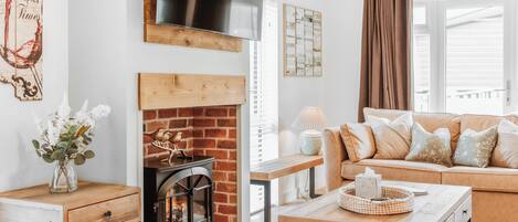 A cozy living room with a fireplace, a sofa, a coffee table, and a wooden side table.