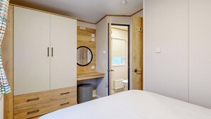 Une chambre à coucher comprenant un lit, une armoire, un miroir et une porte donnant sur une salle de bain.