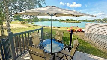 Une terrasse avec une table et des chaises, donnant sur un lac où l’on peut voir des bateaux.