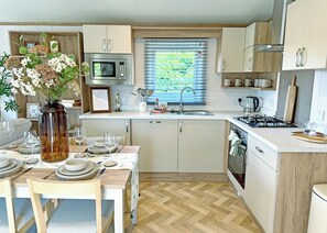 A modern kitchen with a microwave, stove, sink, and dining area set for a meal.