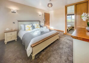 A bedroom with a bed, bedside tables, a mirror, and a view of the outside. - 2 bedroom accommodation in Isle Of Anglesey (Isle Of Anglesey)
