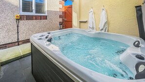 A hot tub with a window, towels, and a brick wall. - 2 bedroom accommodation in Isle Of Anglesey (Isle Of Anglesey)