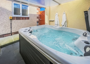 Ein Whirlpool mit Fenster, Handtüchern und einer Ziegelwand.