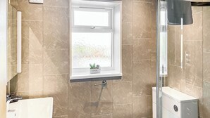 A bathroom with a window, a toilet, a sink, and a shower. - 2 bedroom accommodation in Isle Of Anglesey (Isle Of Anglesey)