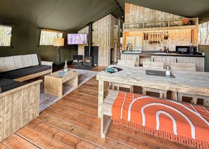 Ein gemütliches Blockhausschlafzimmer mit einer Couch, einem Holzespeisesaal, einer Küchenzeile und einem Kamin.