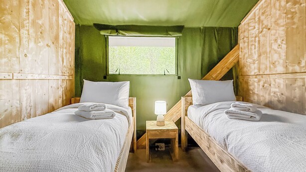 Two wooden bunk beds with white bedding, a nightstand with a lamp, and a window with a view of trees. - 1 bedroom accommodation in Halling (Halling)