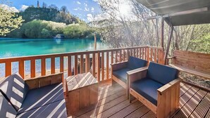 A wooden deck with seating and a view of a turquoise lake.