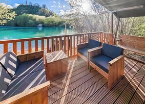 A wooden deck with seating and a view of a turquoise lake.