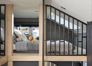Ein modernes Interieur mit einer Treppe, einem Bett mit gemusterten Betttextilien und einem Stofftier auf dem Bett.