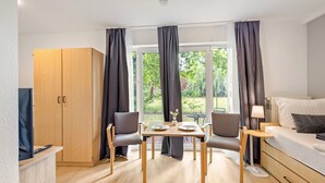 Una habitación moderna con un armario de madera, una mesa de comedor con sillas, un sofá y un televisor.