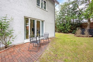 A house with a patio, a brick pathway, and a lawn. - Apartment 'Terrasse Zwei Betten 1-6' with Wi-Fi (Lübeck)