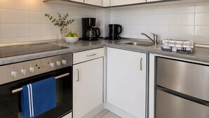 Una cucina moderna con mobili bianchi, elettrodomestici in acciaio inossidabile, forno integrato e macchina da caffè.