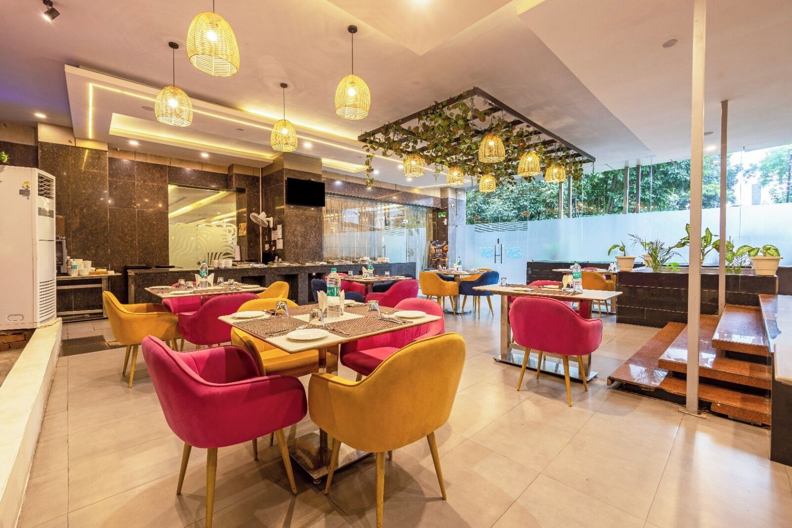 A modern restaurant with a bar area, multiple dining tables with chairs, and hanging pendant lights.