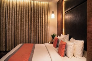 A hotel room with a large bed, a wooden headboard, and a curtain with a floral pattern. - The Sea Valley Azure Gurugram (Gurugram)