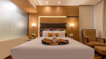 A hotel room with a large bed, a nightstand, a chair, and a wooden headboard.