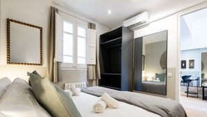 Ein modernes Hotelzimmer mit einem großen Bett, einem Kleiderschrank, einem Spiegel und einer Klimaanlage.