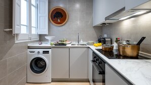 Eine kleine Küche mit Waschmaschine, Spüle, Herd und einem Topf auf der Arbeitsfläche.
