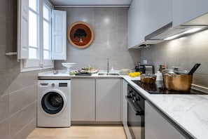 Eine kompakte Küche mit Waschmaschine, Spüle, Herd und einer dekorativen Holzleiste an der Wand.