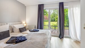 Hotellihuone, jossa on sänky, yöpöytä, ikkuna verhoilla ja näkymä ulos.