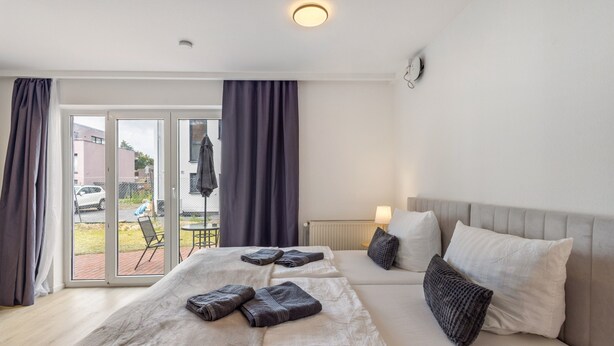 Una habitación de hotel con una cama, un sofá, una mesa y vistas a través de la puerta de cristal.