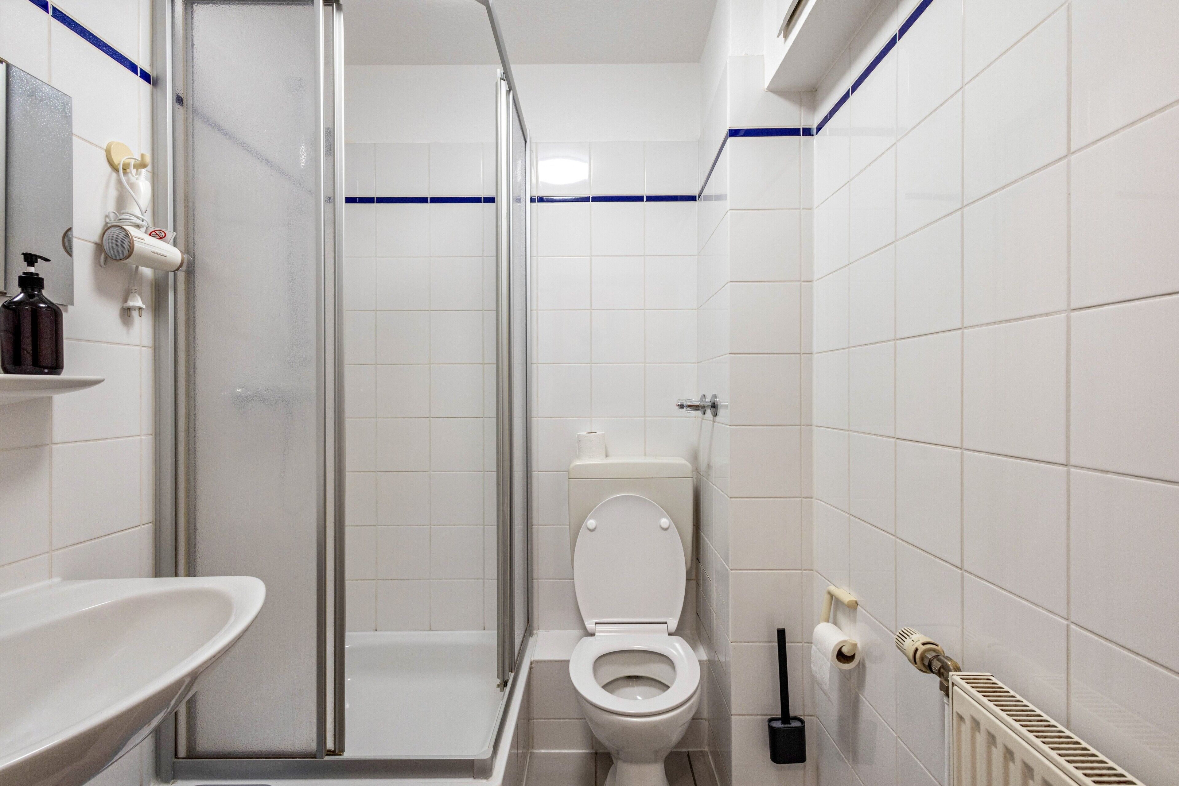 Une salle de bain équipée d’une douche, de toilettes, d’un lavabo et d’un miroir.