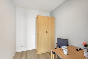 Une pièce comprenant une armoire en bois, une table à manger avec des chaises et un vase avec des fleurs.