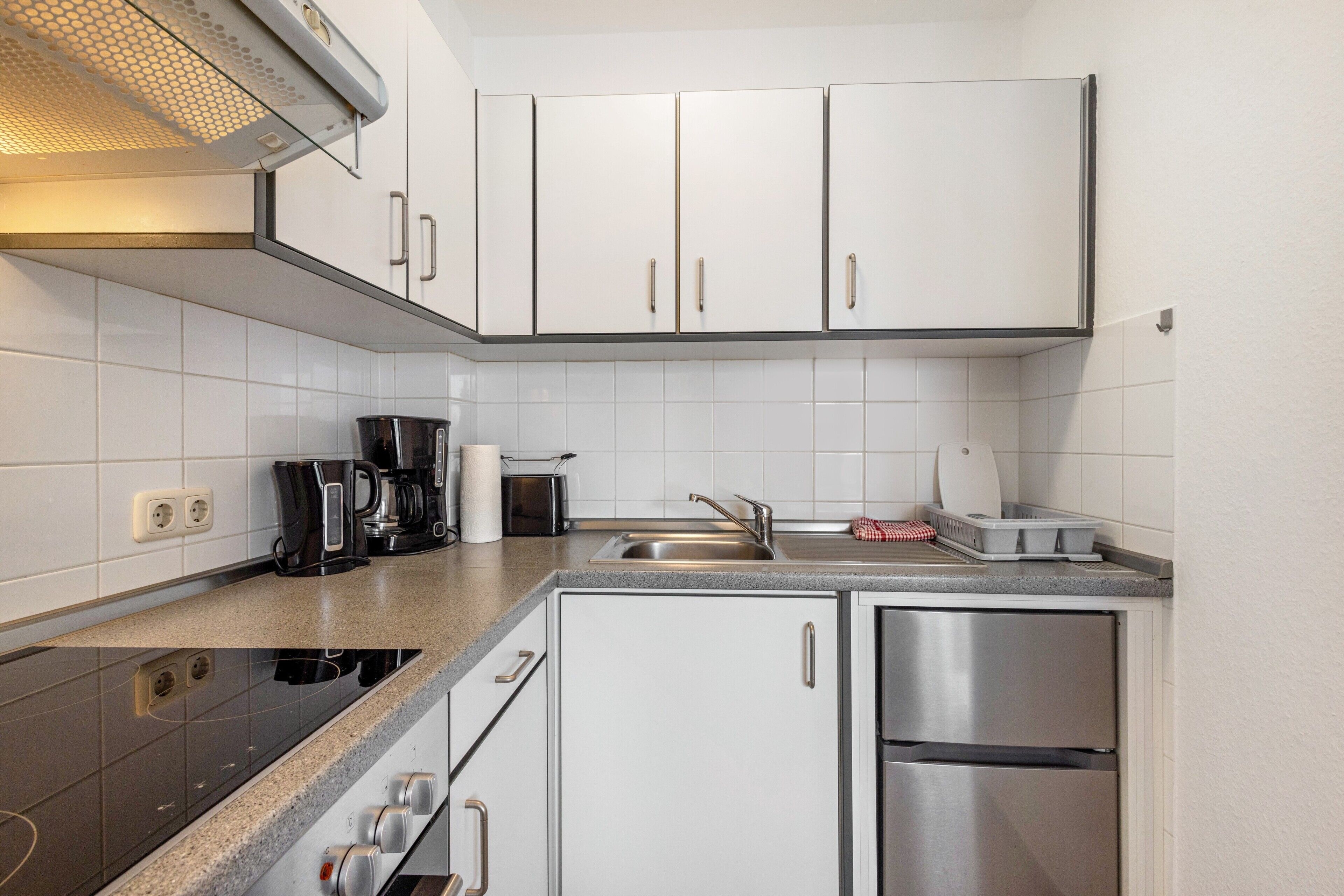 A modern kitchen with white cabinets, stainless steel appliances, and a granite countertop.