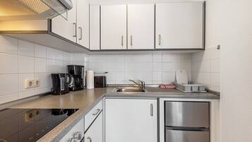 A modern kitchen with white cabinets, stainless steel appliances, and a granite countertop.