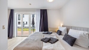 Et hotelværelse med en stor seng, et lille bord og udsigt gennem en glasdør.